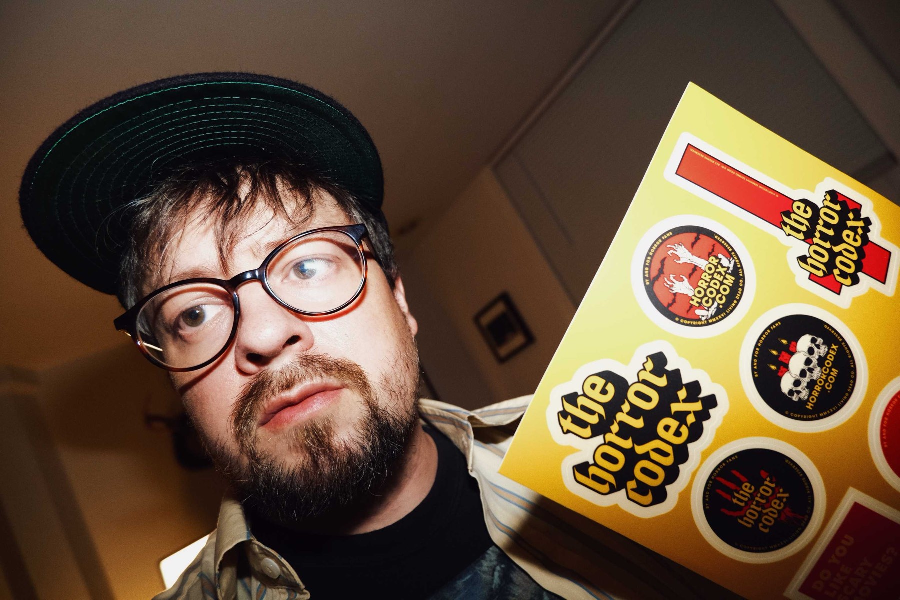 Jon Cole holding a sheet of Horror Codex stickers