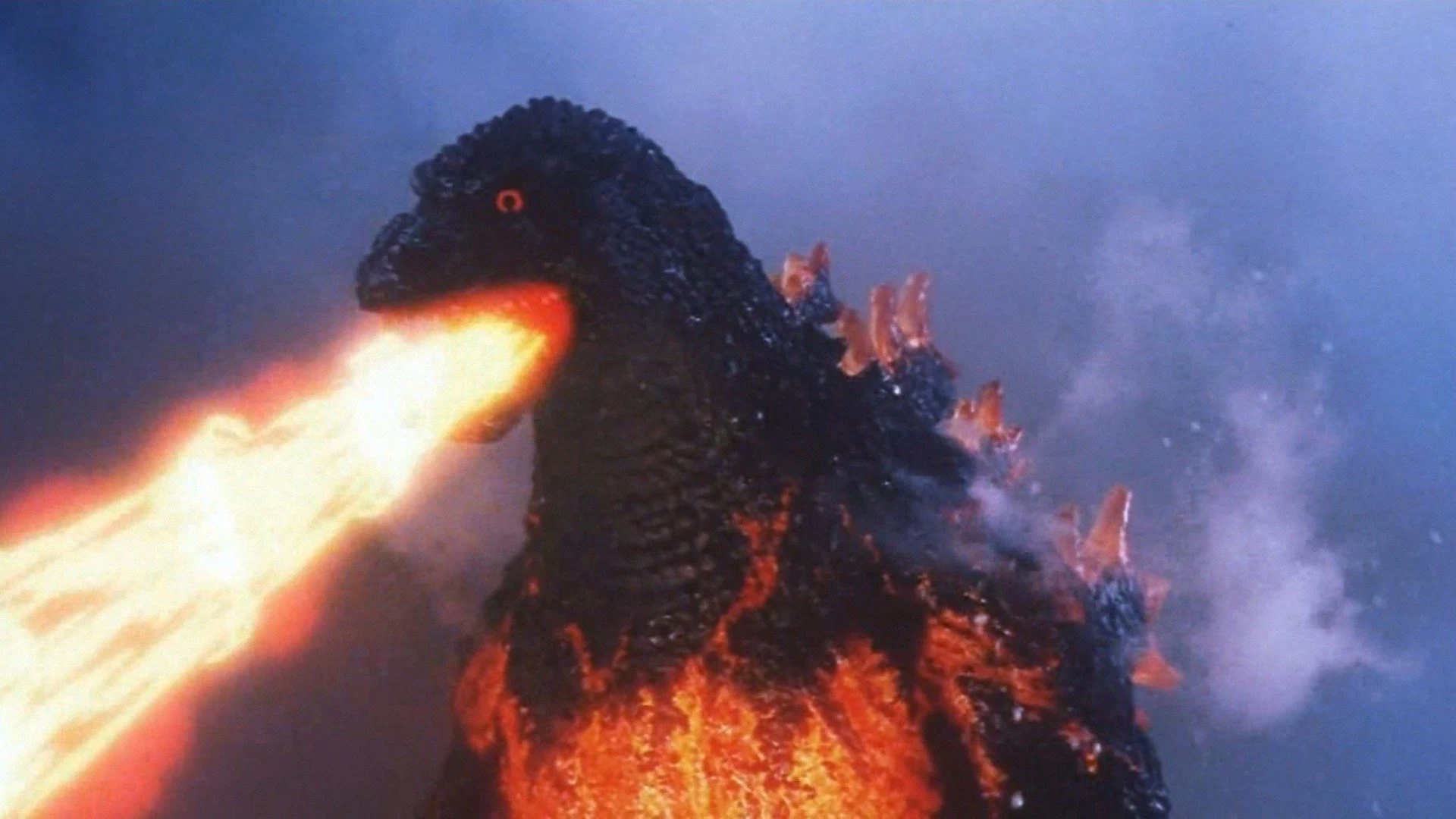 Burning Godzilla from Godzilla vs. Destoroyah (1995): the creature's body glowing with molten orange, exhaling a blast of atomic fire across a smoke-filled sky.
